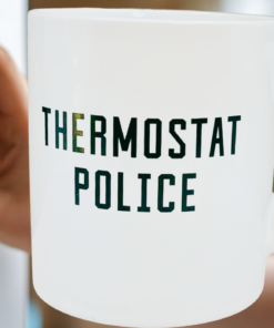 Thermostat Police Mug beside a digital thermostat set to 72 degrees and a police badge