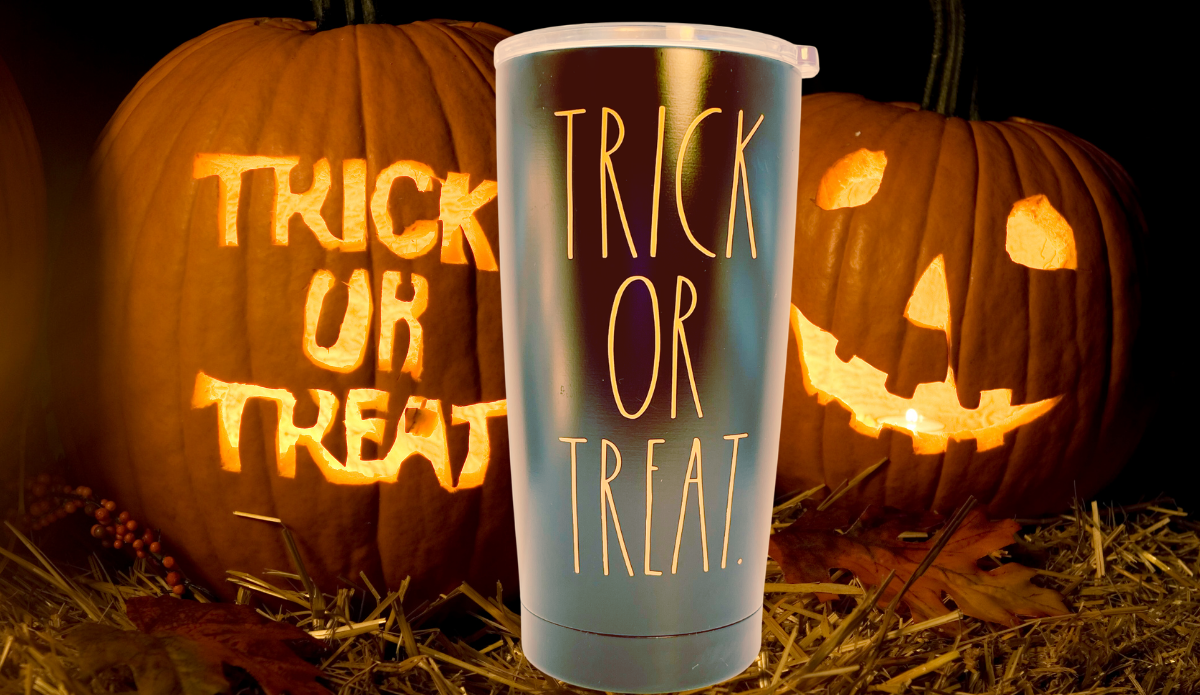 Rae Dunn Trick or Treat Tumbler displayed with glowing jack-o’-lanterns, straw, and autumn leaves