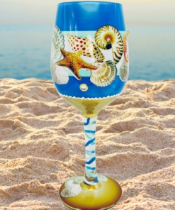 Beach Seahorse Seashell Hand Painted Wine Glass displayed on a sandy beach with ocean waves
