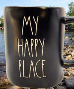 Rae Dunn My Happy Place mug styled by lake with rocks and trees