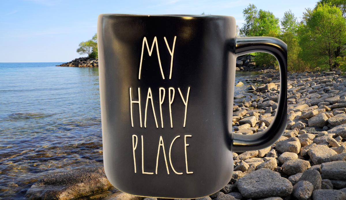 Rae Dunn My Happy Place mug styled by lake with rocks and trees