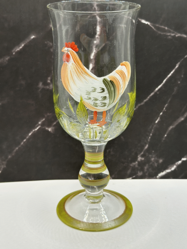 A beautiful, footed goblet features a detailed hand-painted image of a proud rooster standing in lush grass.