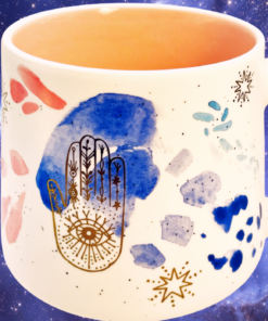Stay Wild Moon Child Hamsa Mug displayed against a glowing galaxy-inspired celestial background