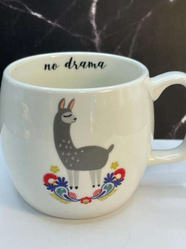 This 17-ounce white ceramic mug, on both sides of the mug features a serene and stylish llama standing tall atop a vibrant bed of colorful flowers.