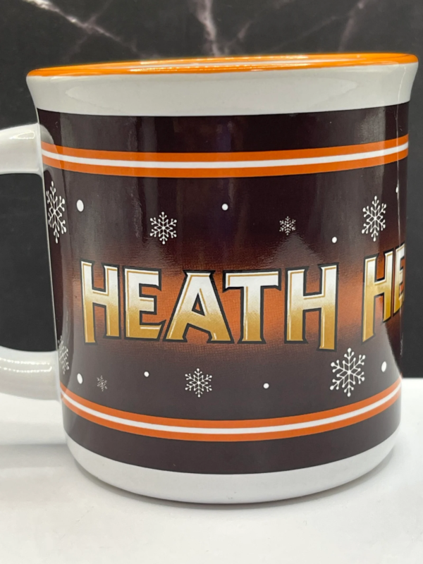 This 10-ounce white ceramic mug features a rich brown background adorned with the iconic Heath logo.