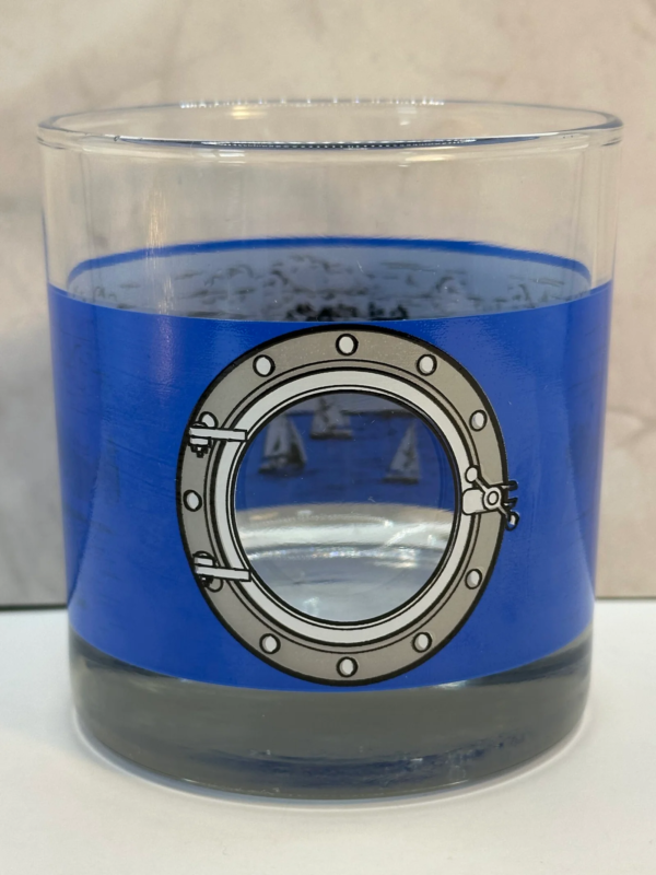 This Royal Caribbean Souvenir Whiskey Glass features a striking porthole design etched into a vibrant blue background on the outside of the glass.No to mention, when you peer through the “window,” and you’ll find a picturesque scene of majestic ships sailing through tranquil waters. Its framed by the lush beauty of a tropical island.