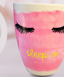 pink eyelash mug with sleep in text beside alarm clock in soft morning setting