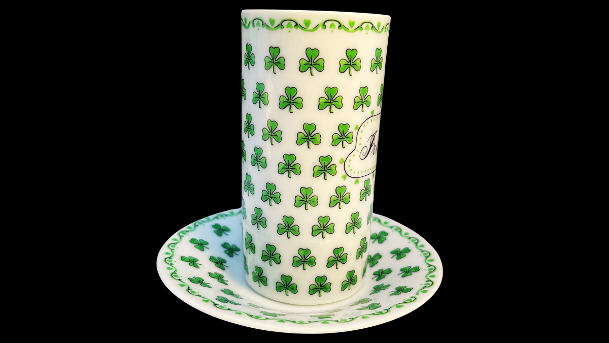 Side handle view of the tall Irish Coffee cup showing the repeating green shamrock pattern across the ceramic surface along with the square-style handle and matching saucer.