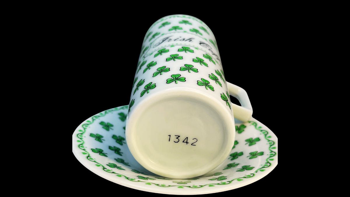 Back view of the Irish Coffee cup and saucer set displaying the repeating green shamrock pattern across both the tall cup and the matching saucer.