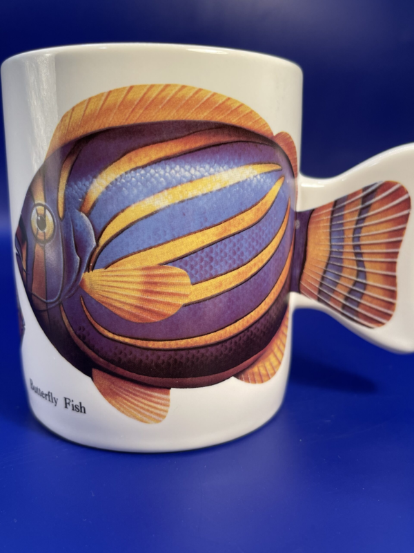This vintage Butterfly Fish Mug is the perfect gift mug for Butterfly Fish Lovers. This is a beautifully designed Coffee Cup with Butterfly Fish.
There are vivid images of different sized Butterfly Fish all over this Vintage Mug with Butterfly Fish. You’ll love how the handle on this Butterfly Fish coffee cup looks like an actual fish fin.
