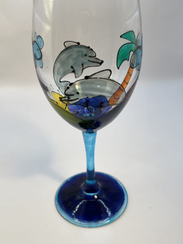 You’ll love the whimsical 3 Dimensional design on this Hand-Gilded Dolphins Wine Glass with Hand Painted Hand Gilded Beach Scene. This Blue Stem Hand Painted Dolphin Wine Glass is beautifully crafted.The hand-gilded and hand painted images make the design slightly raised. Therefore, making this a somewhat 3 Dimensional Dolphin Lovers Wine Glass.
In fact the cobalt blue stem and base of this Hand Painted Dolphins Wine Glass with Beach Scene are a nice accent.