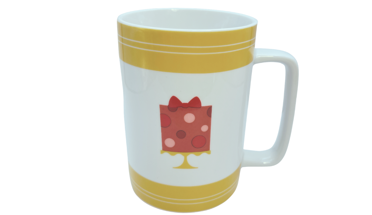 Angled view of Cake Boss Yellow Mini Cakes Porcelain Mug with colorful bakery themed artwork