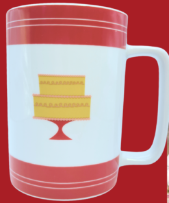 Cake Boss Red Mini Cakes Porcelain Mug displayed in a cozy bakery kitchen with coffee and baked treats