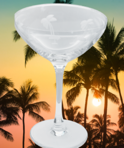 Vintage Etched Palm Tree Cocktail Glass styled against a tropical sunset beach background with palm trees