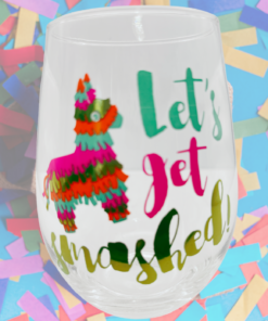 Let’s Get Smashed Piñata Wine Glass styled against a bright confetti background with colorful fiesta artwork and playful party phrase