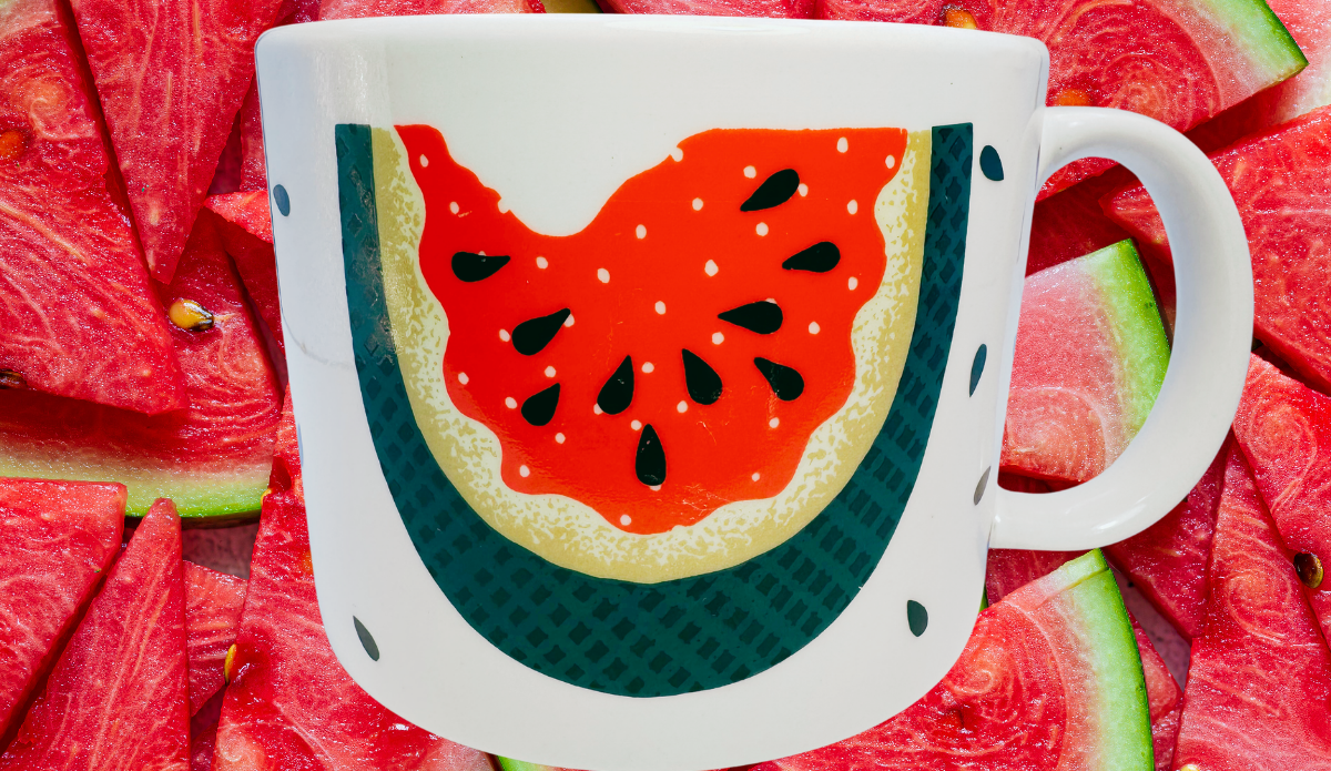 Vintage Tabletops Unlimited Fresh Watermelon Oversized Coffee Mug displayed with fresh watermelon slices in a bright summer setting.