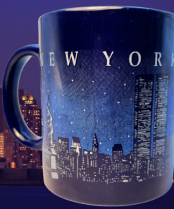 Vintage Cobalt New York Twin Towers Skyline Mug displayed against the Statue of Liberty and Manhattan skyline at night