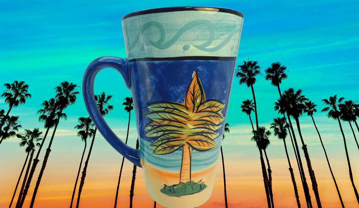 Certified International Palm Tree Latte Mug displayed outdoors at sunset with tall palm trees