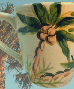 Tabletops Lifestyles Escada Hand Painted Palm Tree Coffee Mug displayed against swaying palm trees and a bright tropical sky
