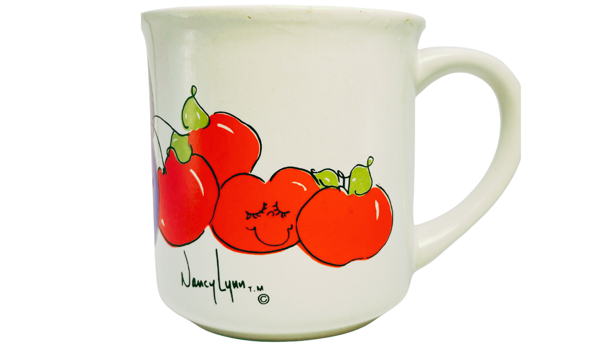Nancy Lynn Plums and Cherries Mug front view with smiling red cherries, small green fruit accents, artist mark, and white handle.