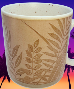 Epoch Collection Panama Tropical Embossed Stoneware Mug displayed against a tropical palm tree sunset backdrop