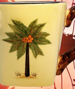 Pacific Rim Palm Tree Hand Painted Ceramic Mug displayed against a tropical palm tree sunset backdrop