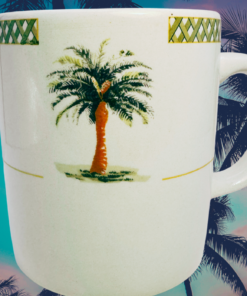 Green Lattice Palm Tree Coffee Mug displayed outdoors beneath tall tropical palm trees