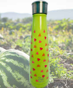 S’ip By S’well Watermelon Cooler Stainless Steel Water Bottle displayed beside whole watermelons in a sunny outdoor field.