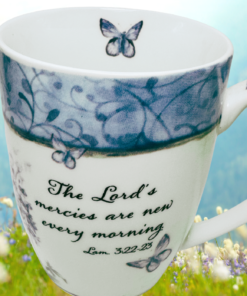 Butterfly Bible verse mug displayed in a blue mountain wildflower meadow scene