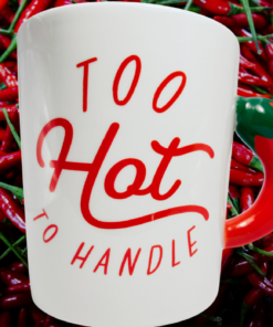 Too Hot To Handle Mug displayed against a background of red chili peppers