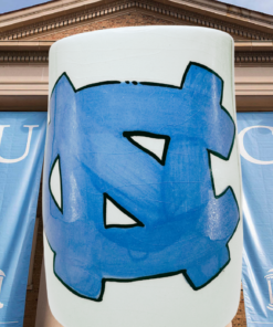 UNC Chapel Hill Hand Painted Mug displayed at University of North Carolina campus with Carolina blue banners