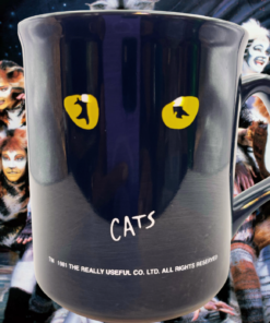 Vintage CATS musical mug displayed in front of performers from CATS The Musical