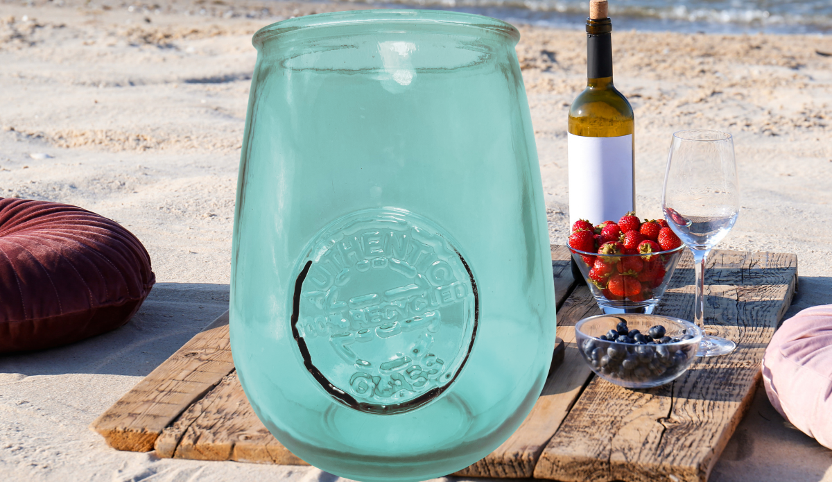 San Miguel teal recycled glass stemless wine glass at a beach picnic with wine berries and ocean backdrop