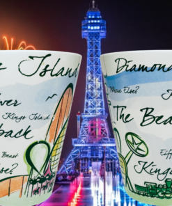 Two angles of Kings Island Ohio Souvenir Mug with illuminated Kings Island Eiffel Tower at night