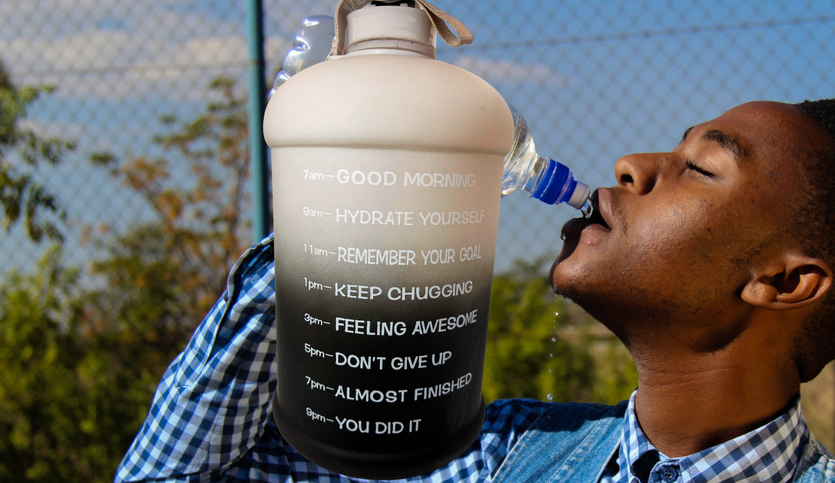 Black Ombre Motivational Water Bottle lifestyle scene with person hydrating outdoors beside motivational time markers