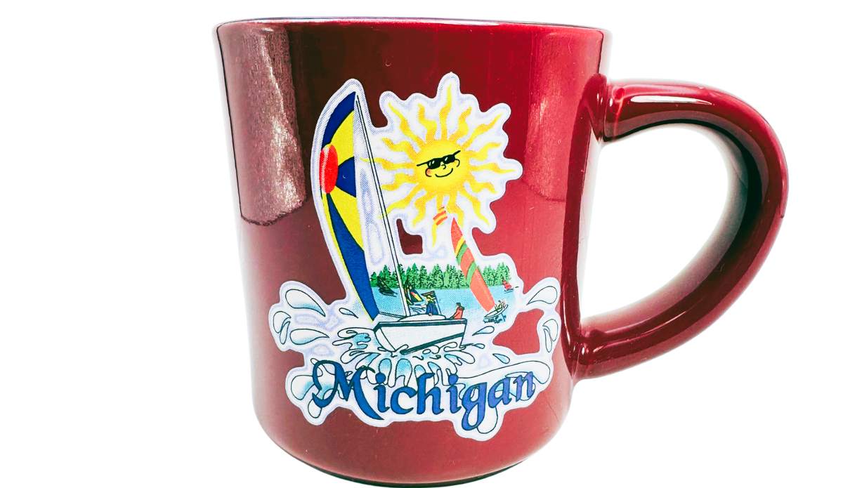 Michigan Sailboat Souvenir Coffee Mug front view with colorful sails, smiling sun, and deep red finish