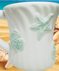 Seafoam Green Seashell Mug displayed on sandy beach with seashells and turquoise water