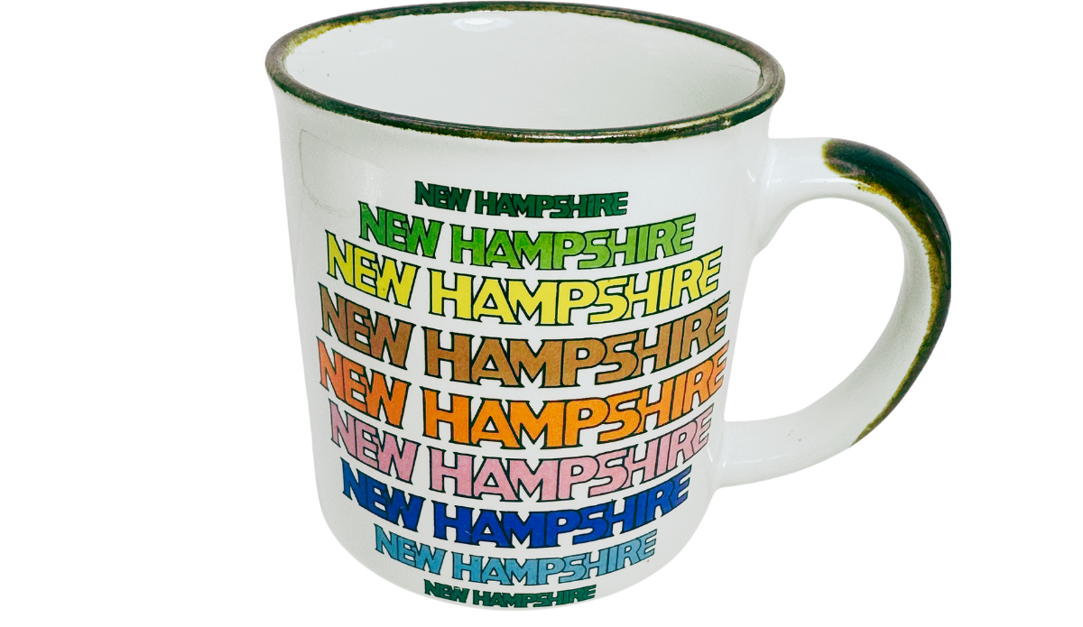 New Hampshire Rainbow Souvenir Mug upper front view with colorful lettering, brown-edged rim, handle, and white interior