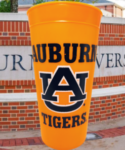 Auburn Tigers Orange Souvenir Cup displayed against an Auburn University campus entrance