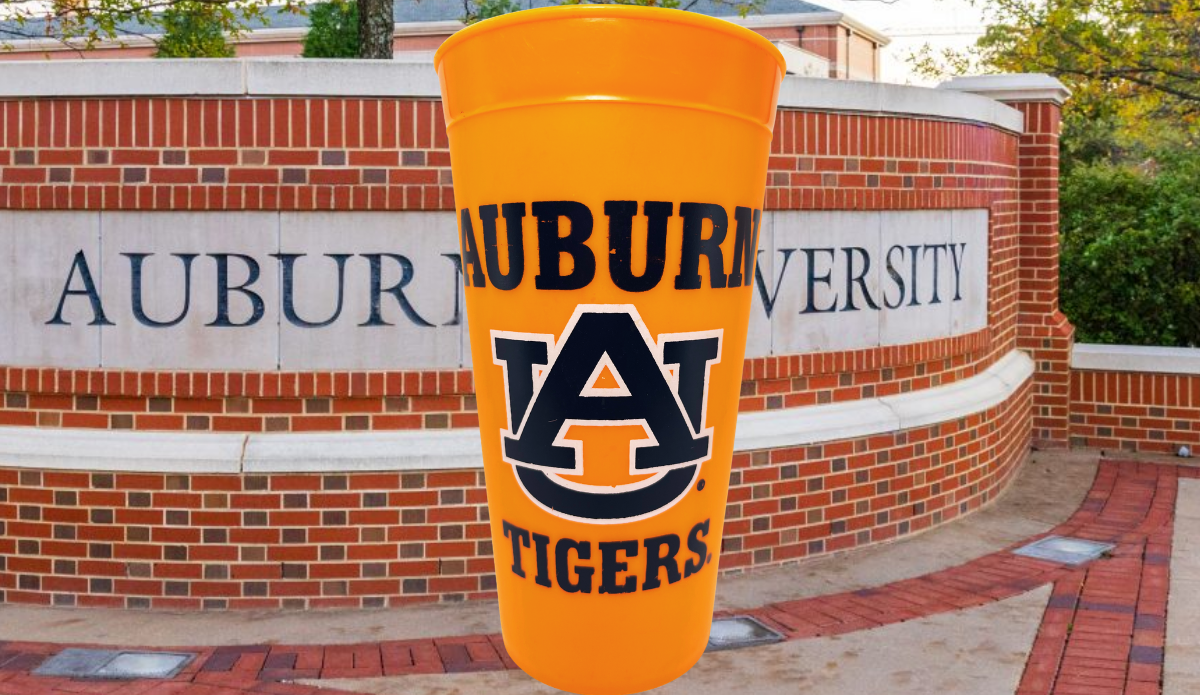 Auburn Tigers Orange Souvenir Cup displayed against an Auburn University campus entrance