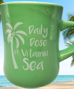 Daily Dose of Vitamin Sea Green Mug displayed on tropical beach with palm trees and ocean
