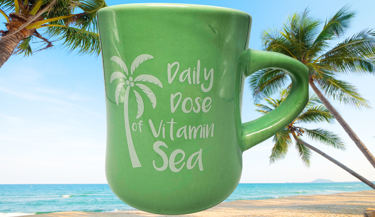 Daily Dose of Vitamin Sea Green Mug displayed on tropical beach with palm trees and ocean