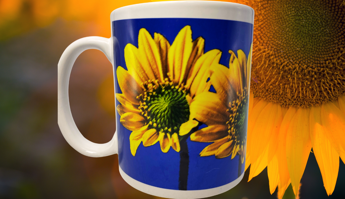 Sunflower Blue Sky Mug displayed with enlarged yellow sunflower imagery and warm golden floral background