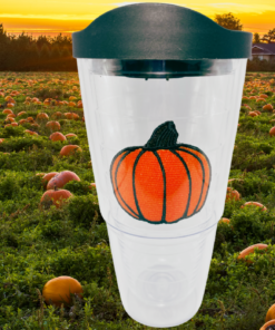 Tervis Pumpkin Tumbler displayed in pumpkin field at sunset with orange pumpkin emblem and black travel lid
