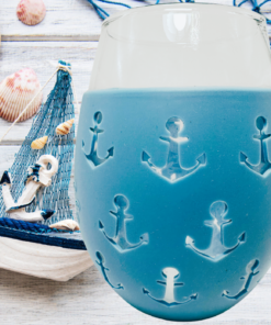 Blue Anchor Stemless Wine Glass with seashells, straw hat, sailboat, and coastal tabletop setting