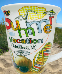 Outer Banks Summer Vacation Souvenir Mug displayed among Outer Banks sand dunes beach grass sea oats and blue sky