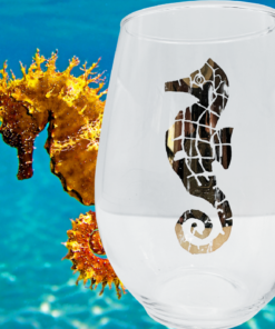 Metallic Seahorse Wine Glass displayed against blue ocean water with real seahorse nearby