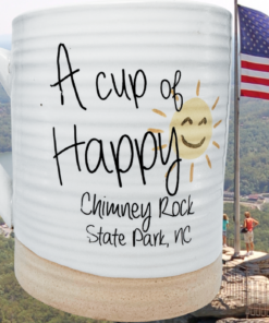 Chimney Rock State Park Souvenir Mug displayed with Chimney Rock State Park mountain scenery in the background