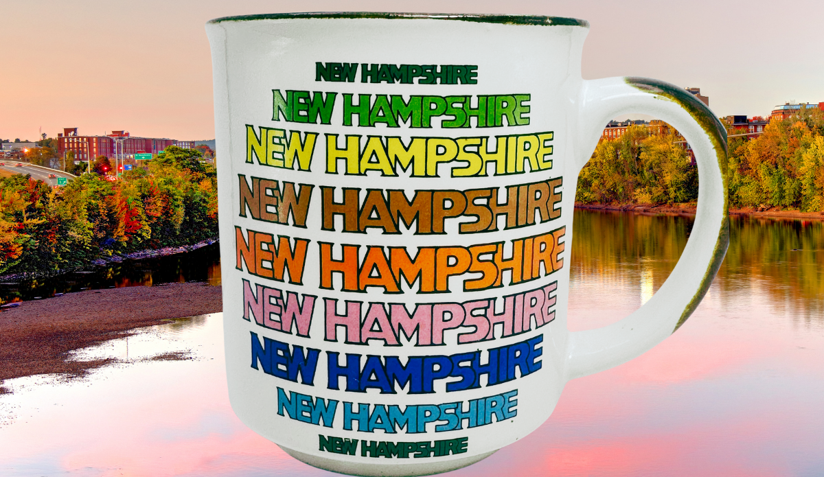 New Hampshire Souvenir Mug displayed against autumn foliage and calm water in New Hampshire
