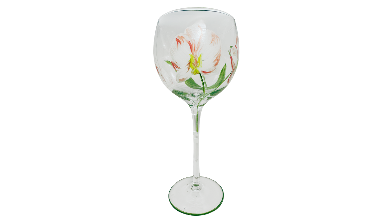 Right side of hand painted peach pink floral balloon wine glass with multiple blossoms, curved green stems, buds, and coral stem bands.